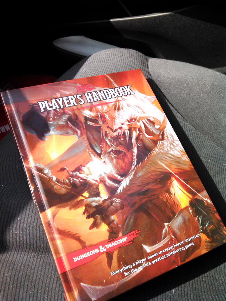The Dungeons & Dragons Fifth Edition Player's Handbook resting on a car seat
